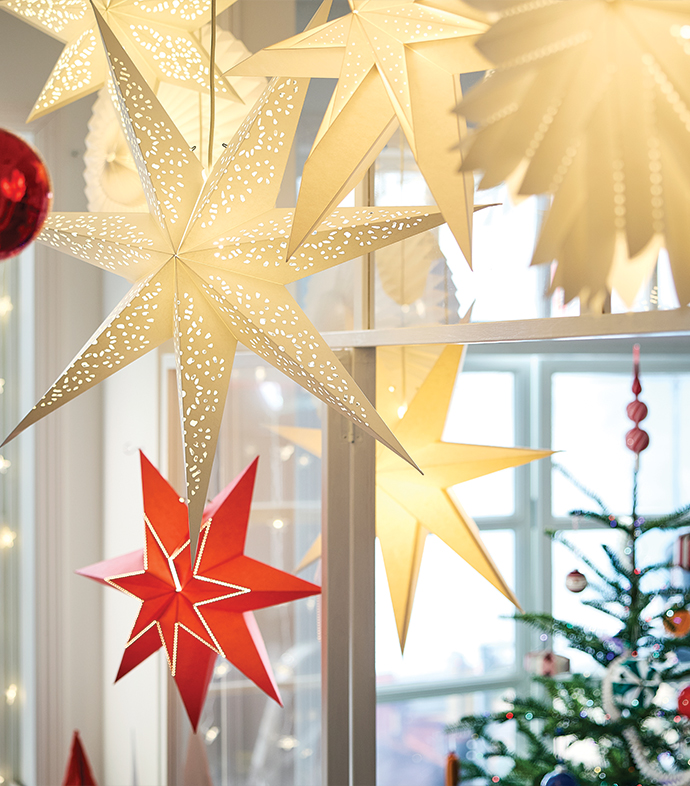 Star-shaped paper lamps hanging in front of a decorated Christmas tree.