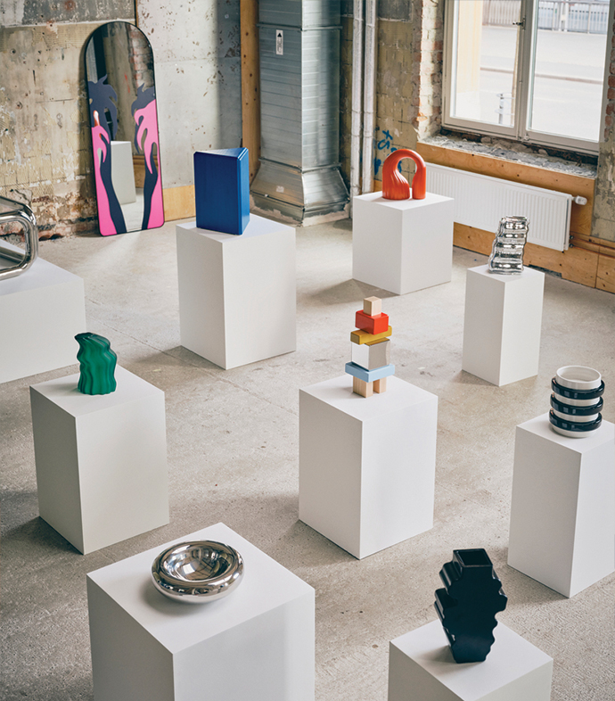 Modern sculptural decorative objects displayed on white pedestals in a gallery space.