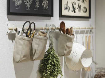 Kitchen utensils and herbs hanging on an organized kitchen wall.